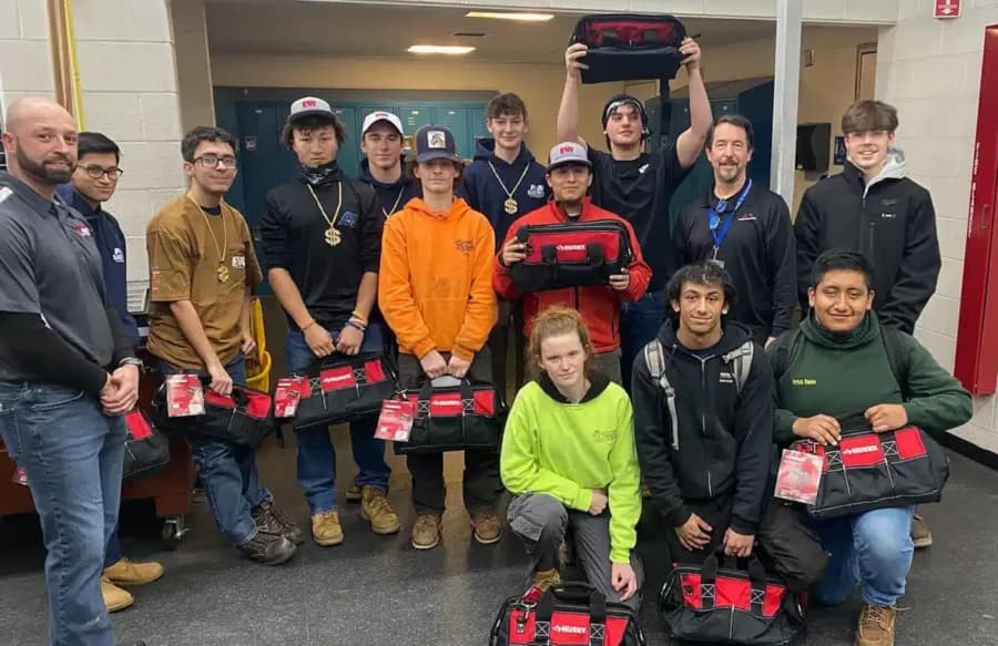 Gabe's electrical team in High school smiling with toolbags.