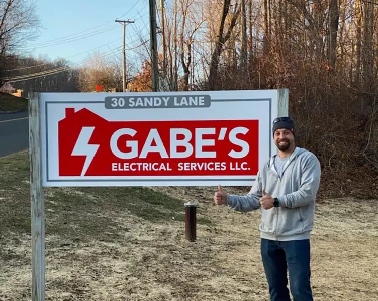 Gabe in front of Gabe's Electrical sign in Brookfield, CT.